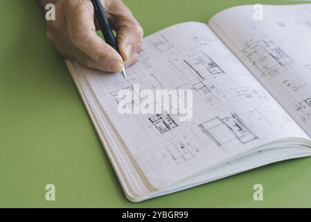 Architect disegna schizzi su notebook su sfondo verde Foto Stock