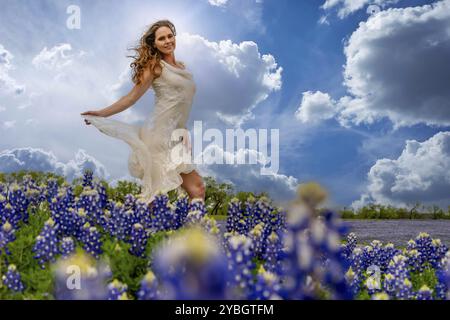 Un bel modello bruna si gode di un campo di fiori Bluebonnet in primavera Foto Stock