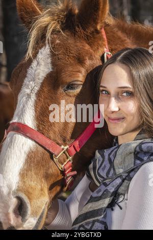 Una bella cowgirl brunetta posa con il suo cavallo prima di un giro in campagna Foto Stock