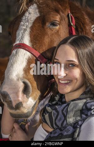 Una bella cowgirl brunetta posa con il suo cavallo prima di un giro in campagna Foto Stock