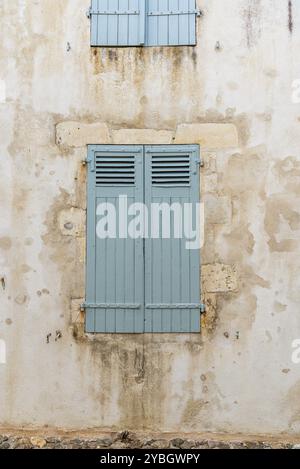 Vecchia finestra con luce di legno verniciato di verde persiane chiuse sul muro bianco Foto Stock