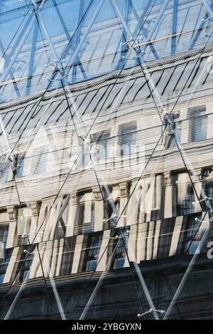 Riflessi di un vecchio edificio in una facciata di vetro dall'architettura moderna Foto Stock