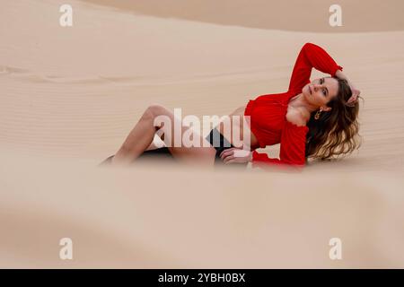 Il modello grazioso abbraccia la bellezza della natura tra le dune di sabbia, incarnando l'eleganza sullo sfondo di un vasto e naturale splendore Foto Stock