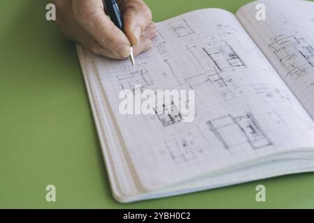 Architect disegna schizzi su notebook su sfondo verde Foto Stock