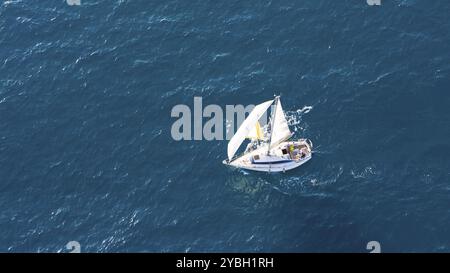 Una piccola barca a vela scivola sulle limpide acque del Mediterraneo vicino a Malaga, in Spagna, sotto un sereno cielo estivo, in Europa Foto Stock