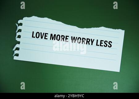 Amore più preoccupazione meno testo scritto su carta strappata vista dall'alto su sfondo verde Foto Stock