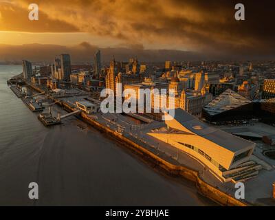 Vista aerea del lungomare di Liverpool al tramonto, con Pier Head e le Three Graces che sovrastano il fiume Mersey sotto un cielo serale colorato. Foto Stock