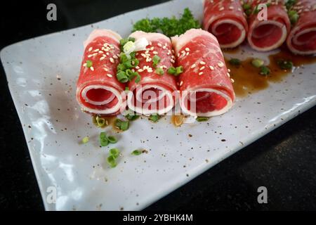 Fetta di spalla di maiale kagoshima kurobuta di prima qualità servita su piatto di ceramica con salsa e scalogno tritato. Foto Stock