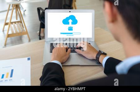 Concetto di storage dei dati, networking e servizio Internet. Vista posteriore di un uomo d'affari che utilizza la tecnologia dell'unità cloud per caricare i file salvati su Internet. Foto Stock