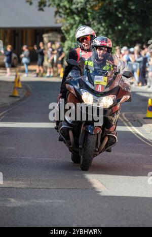 In una soleggiata sesta e ultima tappa della gara ciclistica maschile Tour of Britain del 2024, una scorta motociclistica passa attraverso Framlingham, una città mercato del Suffolk. Foto Stock