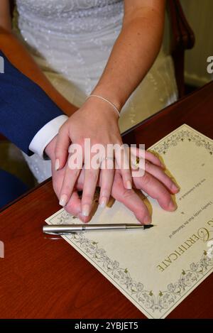 Foto delle mani della sposa e degli sposi quando firmano il certificato di matrimonio Foto Stock