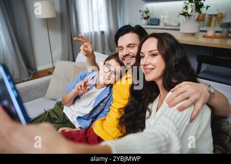 La famiglia cattura momenti di gioia insieme a casa mentre scatta un selfie Foto Stock