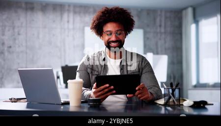 Uomo d'affari afro-americano che utilizza tablet in ufficio editing di foto Foto Stock