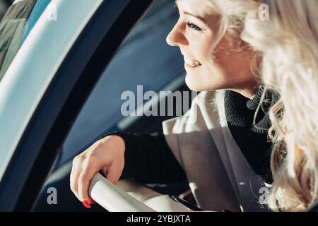 Il turista felice guida la sua auto in una nuova città, cercando indicazioni con entusiasmo in una giornata di sole, incarnando la gioia di viaggiare e scoprire Foto Stock