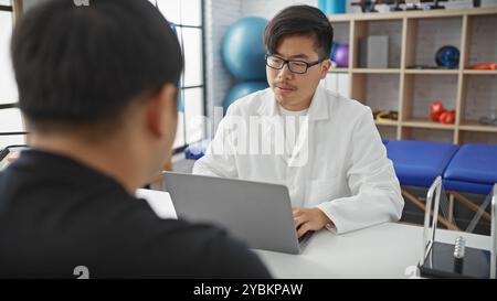 Due uomini, un medico e un paziente, si impegnano in una discussione all'interno della sala consultiva di una clinica moderna. Foto Stock