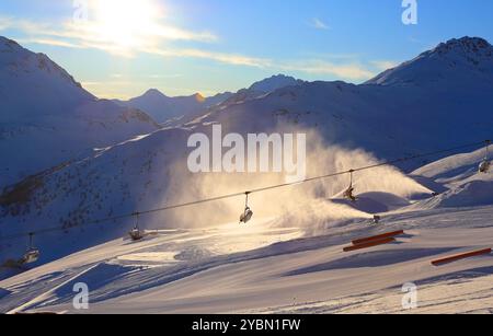 Seggiovia e cannoni da neve funzionanti al sole luminoso sullo sfondo delle Dolomiti innevate, Italia Foto Stock