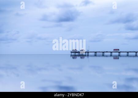 Una vista tranquilla del molo di Clearwater Beach, Florida, USA. Il lungo molo si estende su acque calme e riflettenti, con piccole capanne arroccate. Foto Stock