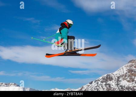 Sciatore che prende un po' d'aria dopo il lancio di un salto in uno snowpark tra le montagne innevate. Livigno, Italia Foto Stock