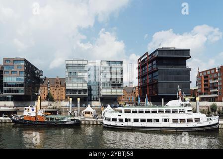 Amburgo, Germania, 7 agosto 2019: Paesaggio urbano del canale Sandtorhafen con navi ormeggiate sul porto e edifici residenziali moderni di lusso. Giornata di sole Foto Stock