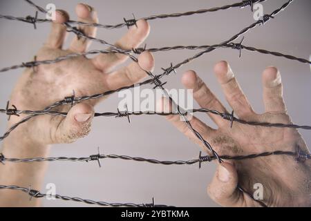 Le mani di presa del filo spinato nel segno di fuggire con lo sfondo bianco Foto Stock