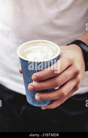 Tazza di carta usa e getta per il caffè di Young Man Holding in Street Foto Stock