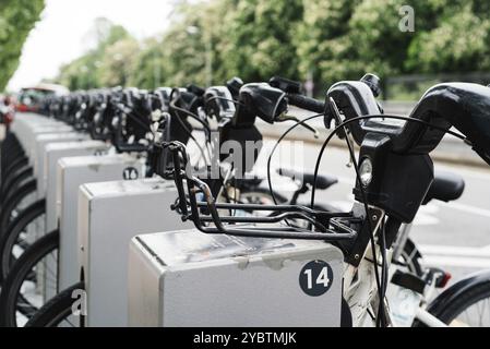 Fila di biciclette parcheggiate. Le biciclette bianche si trovano su un parcheggio a noleggio in un punto di noleggio biciclette sulla strada della città. Concetto di trasporto pubblico. SAV Foto Stock