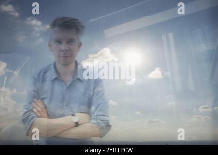 Vista in alzata la riflessione di un imprenditore caucasico guardando fuori da una finestra di ufficio Foto Stock