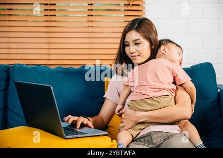 Una madre lavora in modo efficiente dal suo ufficio domestico digitando sul suo laptop mentre sua figlia dorme Foto Stock