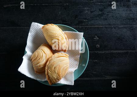 Un piatto di sfoglia malese fritta al curry o epok-epok isolato su sfondo scuro. Noto anche come Karipap Pusing. Foto Stock