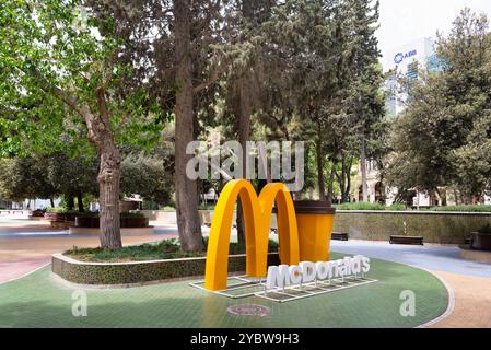Baku, Azerbaigian - 5 maggio 2024: Un importante arco e una coppa di McDonald's dorati sono esposti in un parco in via Nizami Foto Stock