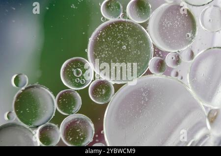 Primo piano di bolle d'olio sulla superficie dell'acqua con sfondo bianco morbido. Adatto per il design e la carta da parati Foto Stock