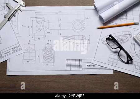 Diversi disegni tecnici, vetri, calibro a corsoio e matita su tavolo in legno, vista dall'alto Foto Stock