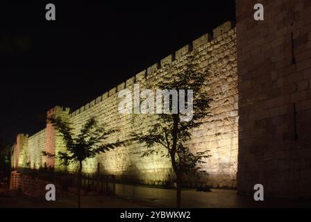 Una vista notturna di una sezione degli antichi bastioni in pietra e delle mura della città Vecchia di Gerusalemme, illuminata dalla luce artificiale in Israele. Foto Stock