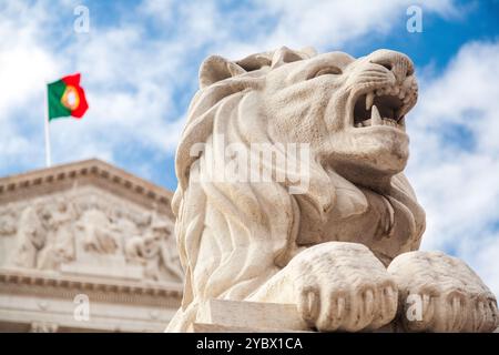 La maestosa scultura del leone si erge orgogliosamente davanti alla facciata neoclassica del Palazzo Sao Bento sotto un cielo nuvoloso a Lisbona. Foto Stock