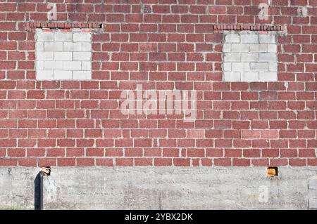 Parete esterna dell'edificio a blocchi con due finestre sigillate Foto Stock