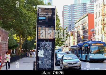 Un MTA NYC Transit M15 Select Bus con una mostra 'non in servizio' passa accanto ad un cartello degli arrivi che mostra i primi autobus disponibili che arrivano molto tardi. Foto Stock