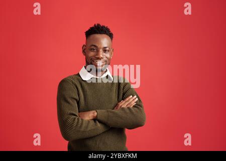 Ritratto dell'uomo sorridente in maglione verde su sfondo rosso Foto Stock