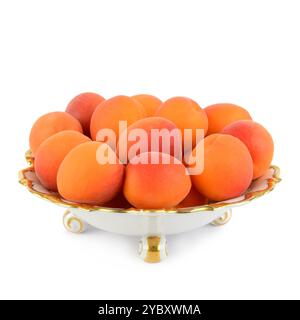 Albicocche mature e succose in un cestino di frutta in porcellana d'annata isolato su sfondo bianco. Foto Stock