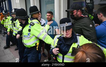 Brighton Regno Unito 7 agosto 2024 - Un commerciante locale che lavorava nelle vicinanze viene coinvolto nelle proteste ed è protetto dalla polizia come protesta antirazzista contro le recenti manifestazioni di estrema destra in tutto il Regno Unito . Ci sono state rivolte razziali dopo l' omicidio di 3 bambini a Southport a luglio : Foto Stock