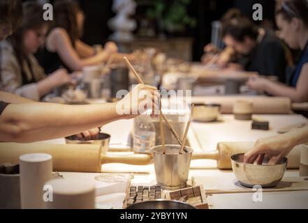 Un gruppo di persone impegnato in un laboratorio di ceramica, incentrato sulla produzione di ceramiche e sulla creatività in un ambiente collaborativo. Vari strumenti e accoppiamenti Foto Stock