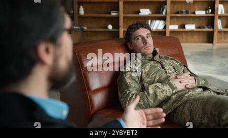 Psicologo parlante paziente cliente ufficiale caucasico uomo soldato militare veterano dell'esercito ragazzo disteso divano parlare psicoterapeuta analisi Foto Stock