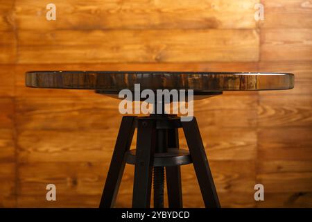 Un elegante tavolo rotondo che mostra uno splendido piano in legno pietrificato, elegantemente esposto su un caldo sfondo in legno, perfetto per interni moderni Foto Stock