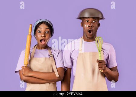 Coppia afro-americana scioccata ricoperta di farina che cuoce insieme su sfondo colorato Foto Stock