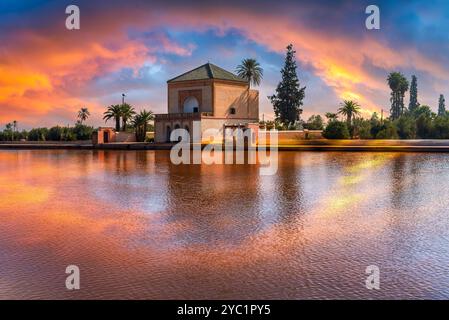 Il Padiglione e i giardini Menara di Marrakech, Marocco, catturati al tramonto con riflessi vibranti sul tranquillo lago, che mostra l'iconico arco marocchino Foto Stock