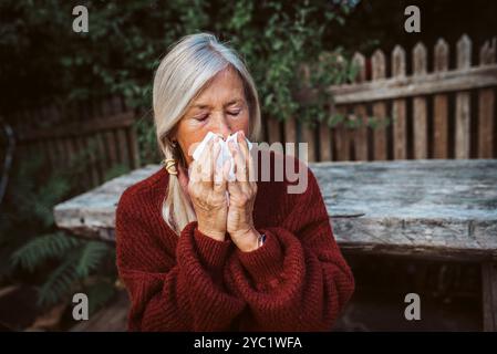 Le donne anziane si sentono male, soffiando il naso che cola e chiuso nel tessuto e starnuto. Foto Stock