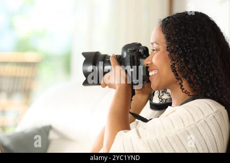 Profilo di un fotografo nero che scatta foto con una fotocamera dslr a casa Foto Stock