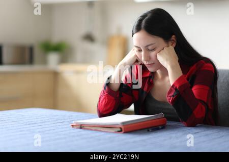 Studente asiatico che impara a leggere note in cucina a casa Foto Stock