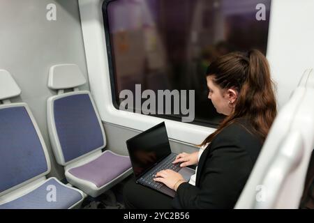 Giovane donna d'affari che lavora su un notebook mentre viaggia in treno Foto Stock