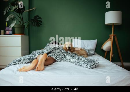 Un giovane è sdraiato a letto con un cane, dorme Foto Stock