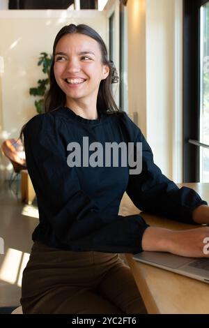 Una donna sorridente sul suo laptop in un bar. Foto Stock